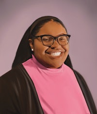 a portrait of a black woman wearing glasses and a pink shirt